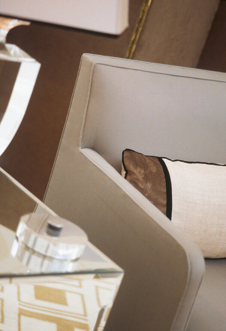 Modern upholstered sofa with striped cushion next to mirrored glass side cabinet with table lamp