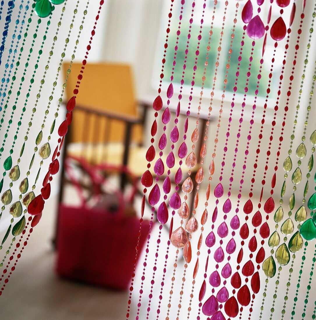 Multi color beaded curtain with chair and basket behind