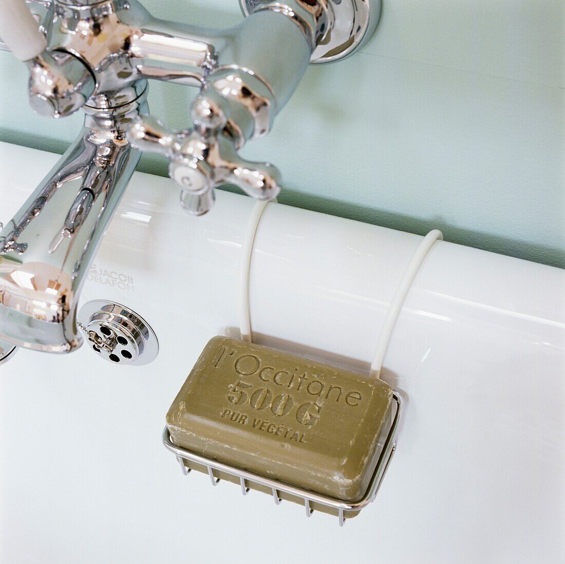 Soap in rack hanging next to silver bathroom taps