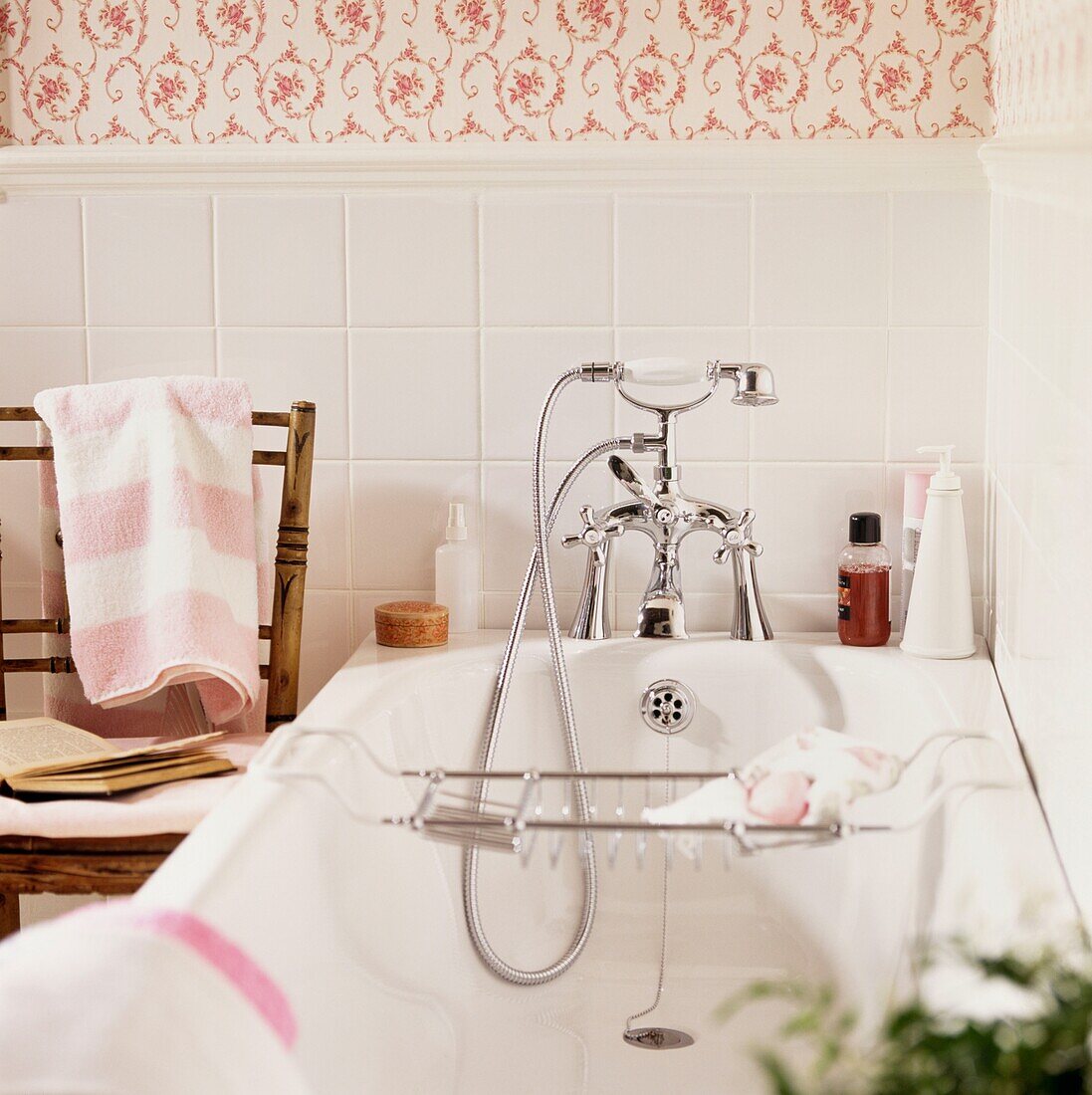 Duscharmatur in der Badewanne unter einer blumengemusterten Tapete