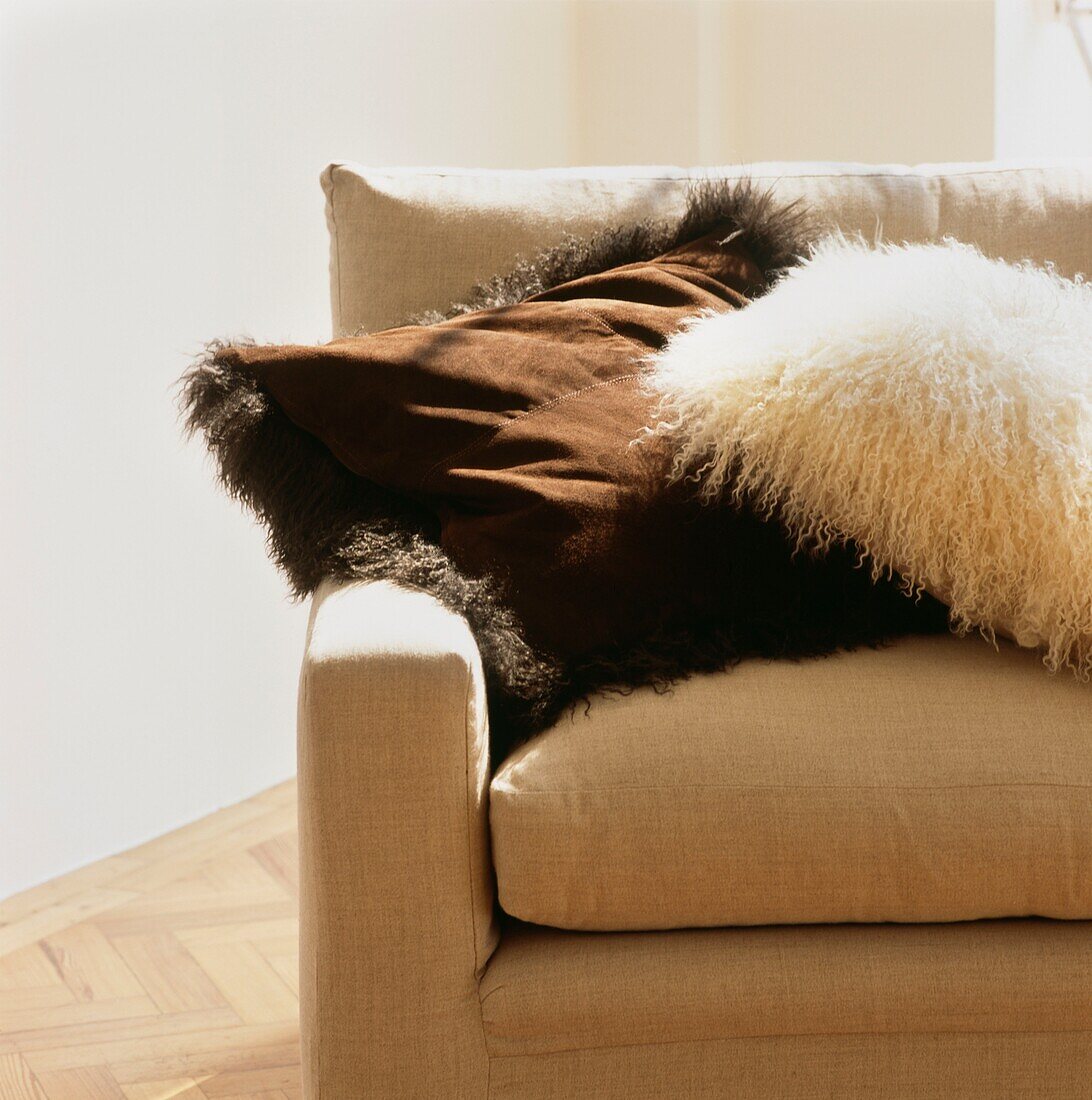 Pelz- und Wildlederkissen auf cremefarbenem Sofa