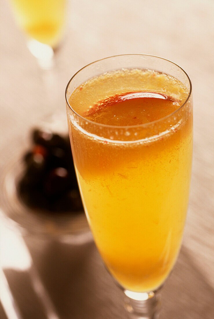 Two glasses of Bellini, Champagne with pureed peaches and peach liqueur on a glass tray with a dish of olives