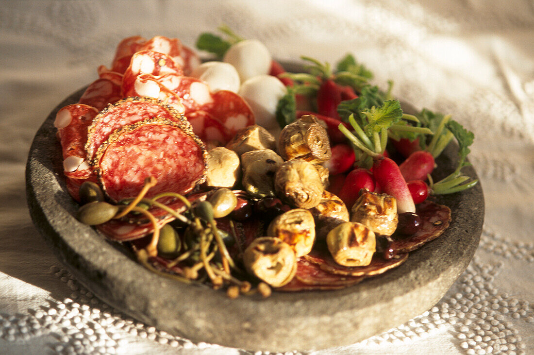 Mediterrane Antipasto mit verschiedenen Salamis Artischocken Kapernbeeren Wachteleier und Radieschen