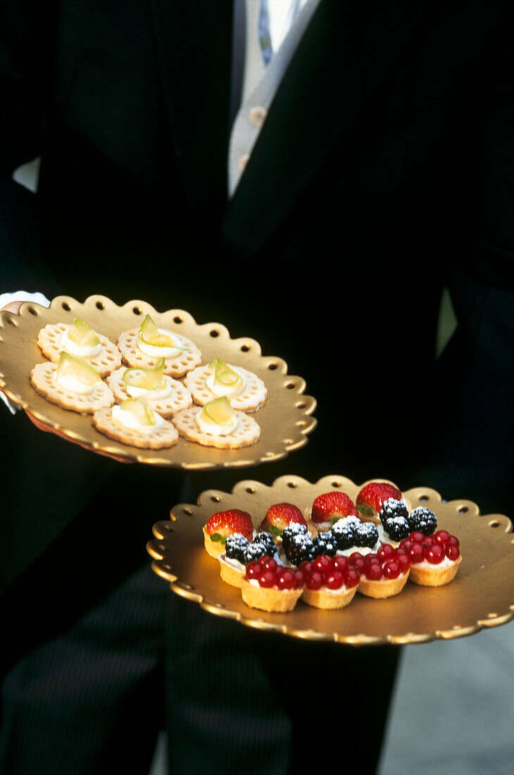 Kellner serviert Dessert-Canapes und Obsttörtchen