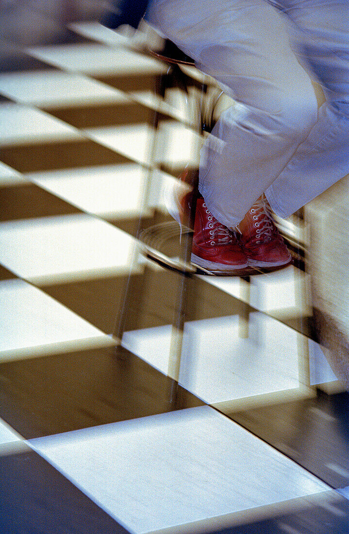 Sitting at a tapas bar in Spain with Jeans and red shoes against a black and white tiled floor