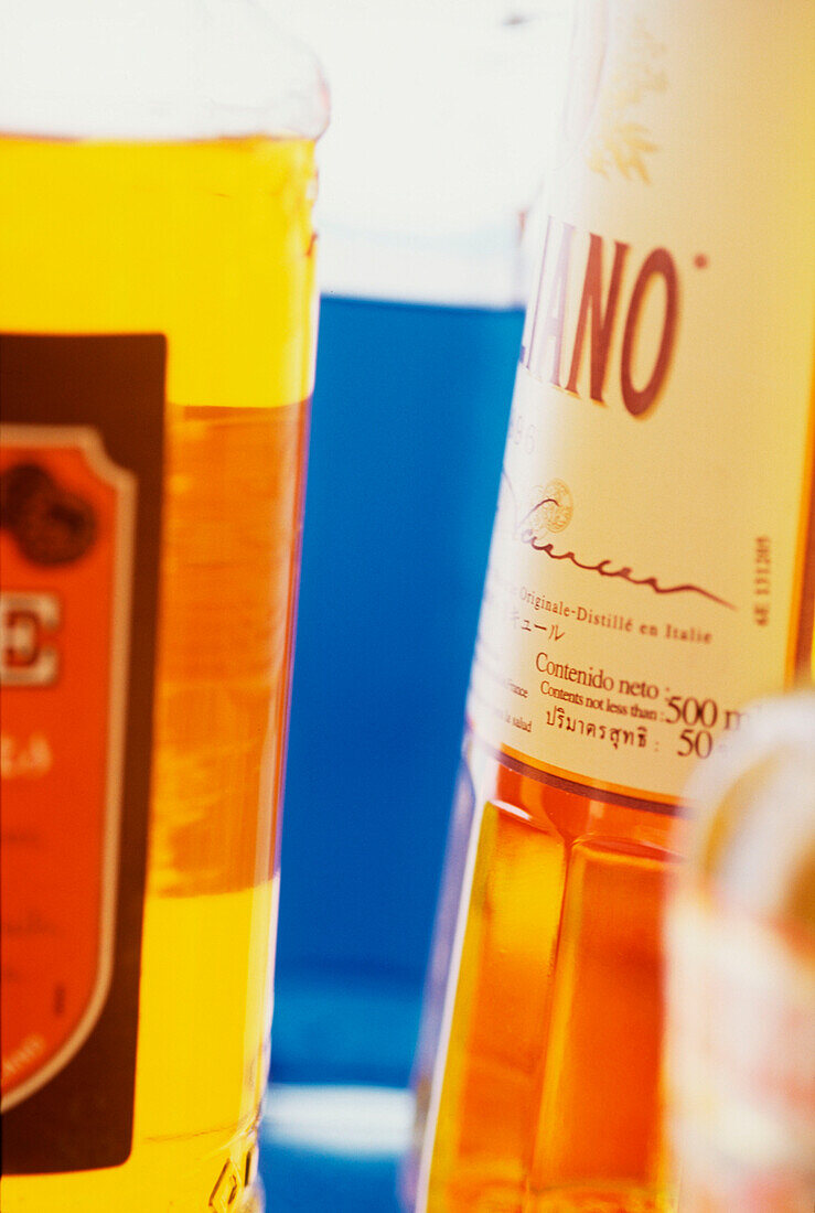 Detail of cocktail bar shelf with coloured spirit and liqueur bottles