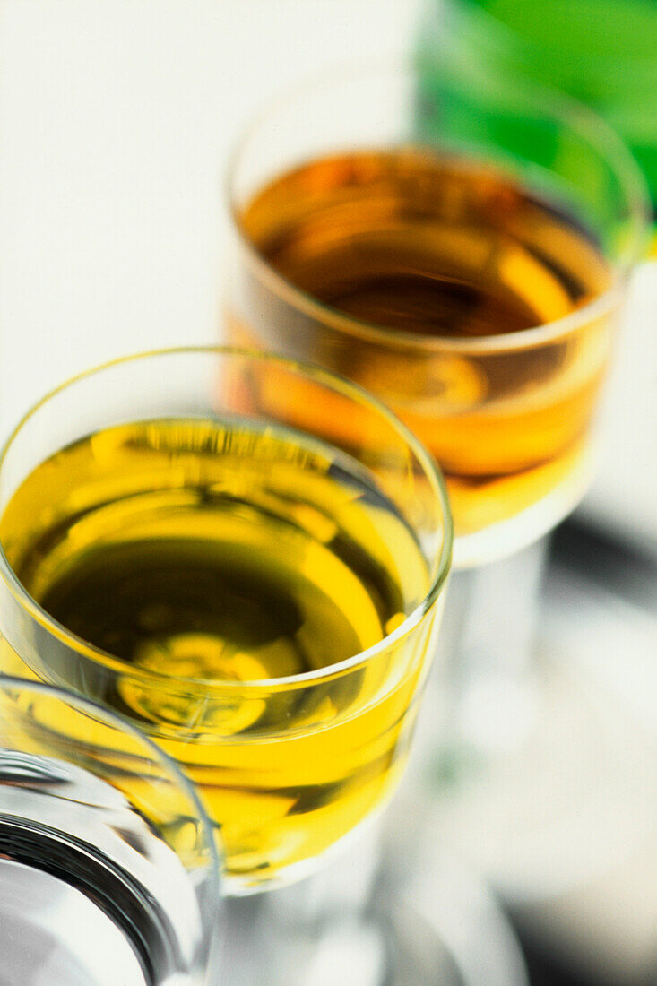 Overhead shot of a row of Amber and Green coloured Liqueurs in glasses