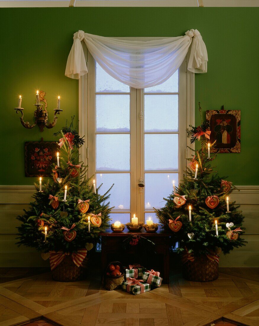 Christmas trees decorated with lit candles and heart-shaped ornaments