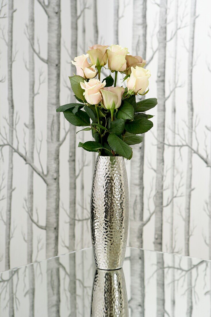 Metallvase auf verspiegelter Tischplatte mit frischen Rosen vor Tree Silhouette-Tapete