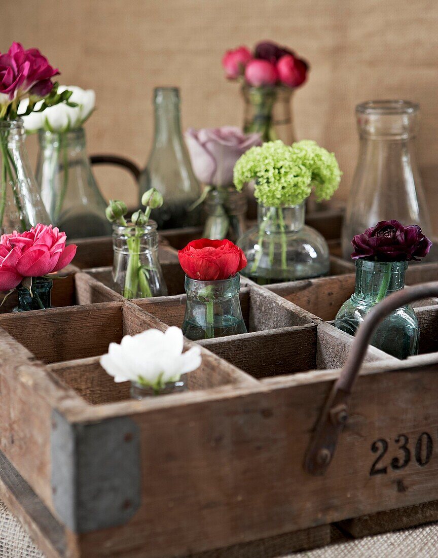 Single stem flowers in vases in vintage wooden crate