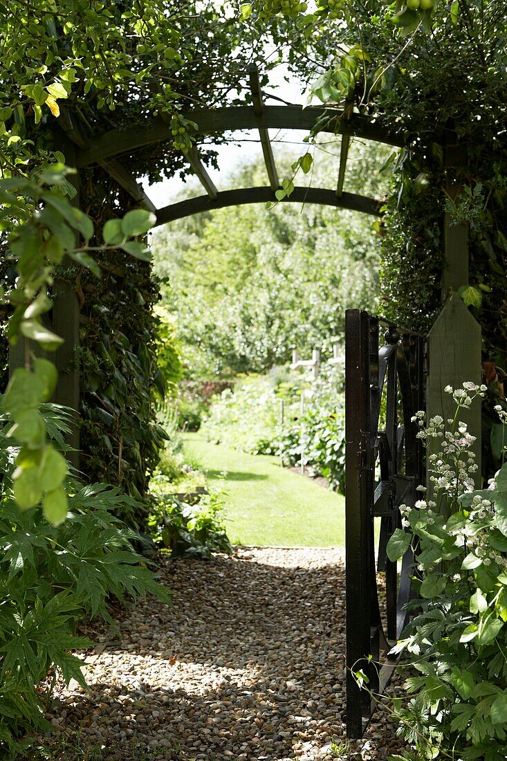 View through paved stone archway with gate to grass field