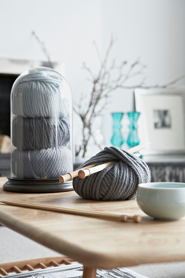 Ball of grey wool with knitting needles on coffee table in London home   UK