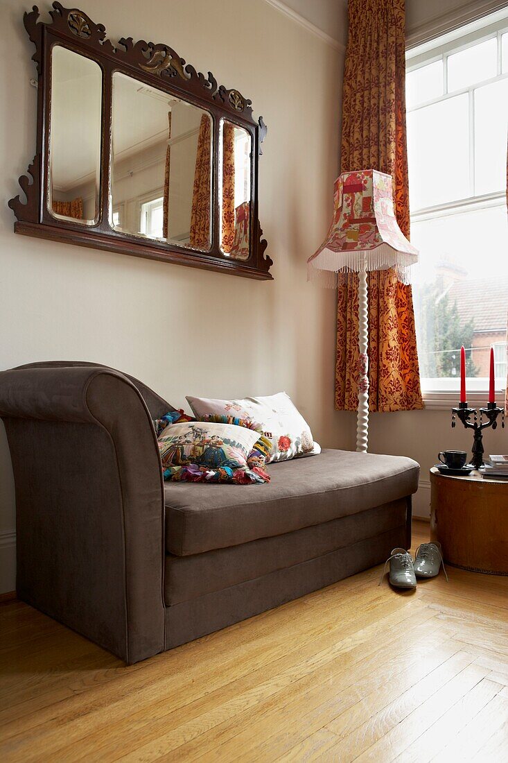 Brown chaise longue under antique mirror at window of London home   England   UK