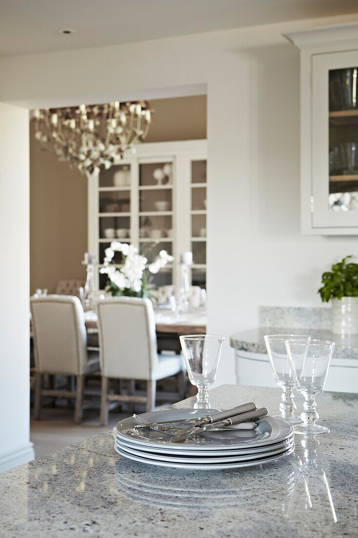 Tableware on work surface in kitchen with view to dining room in contemporary home