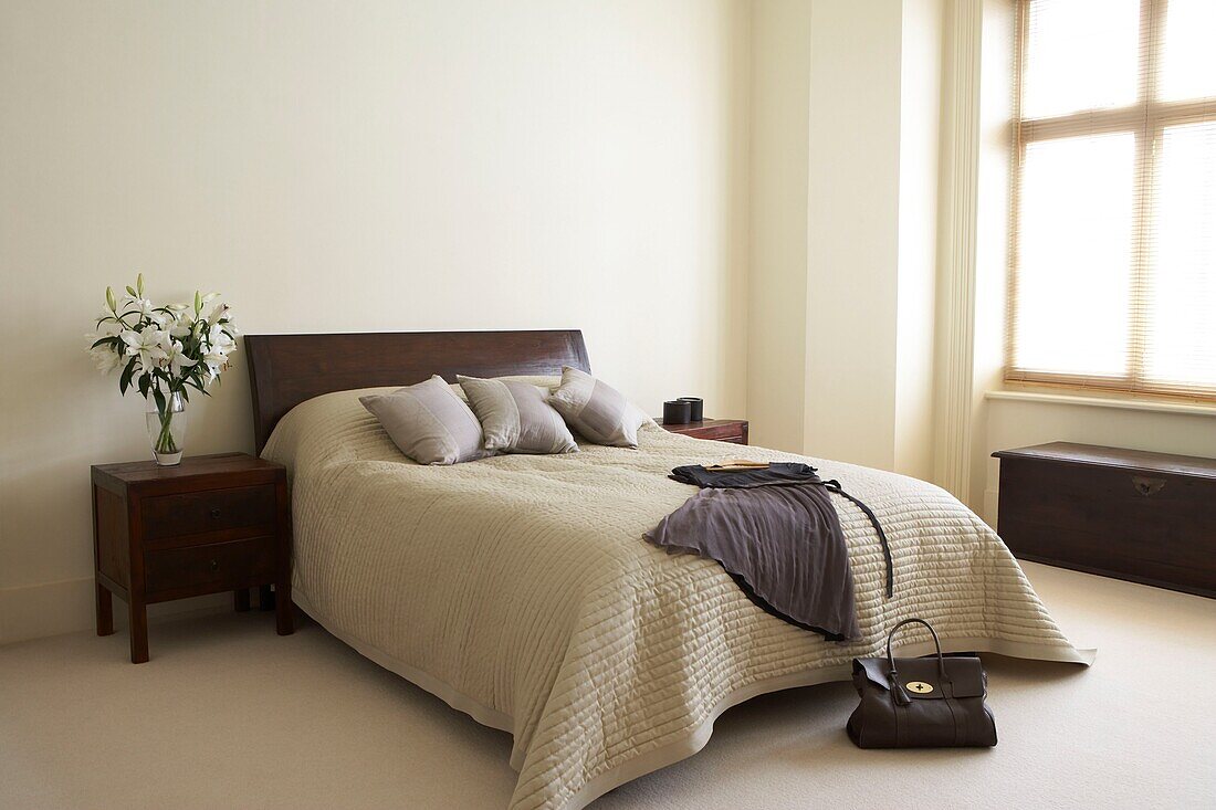 Large Neutral double bedroom with dress and handbag and bouquet of white Lilies