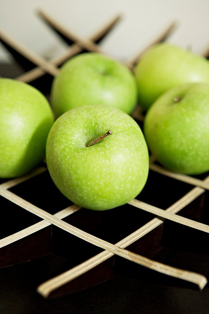 Fünf Äpfel auf einem hölzernen Obstständer