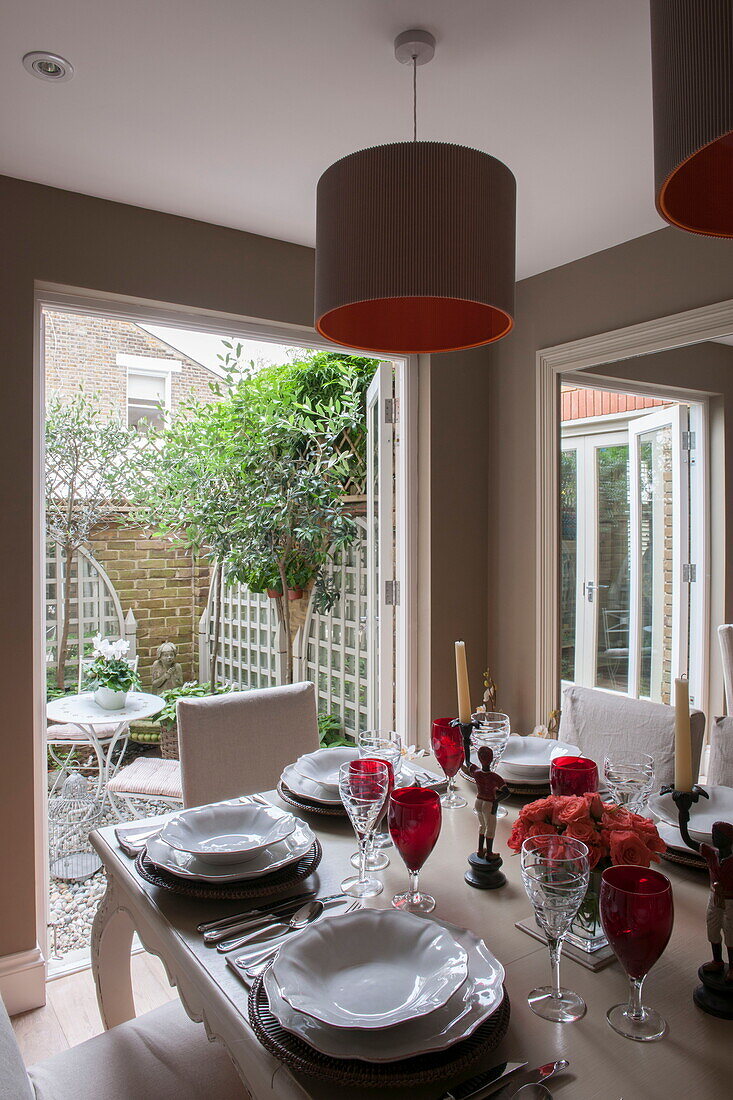 Dining room with view through open doorway to courtyard in Battersea home,  London,  England,  UK