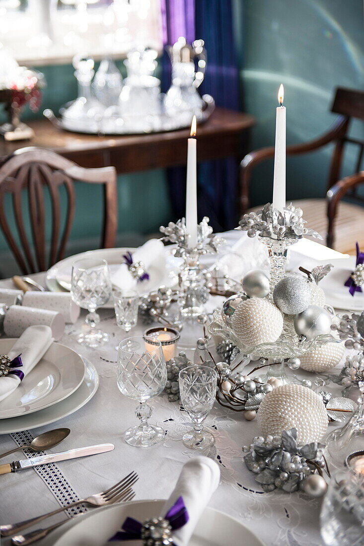 Lit candles and Christmas ornaments on dining table in Tiverton farmhouse  Devon  UK