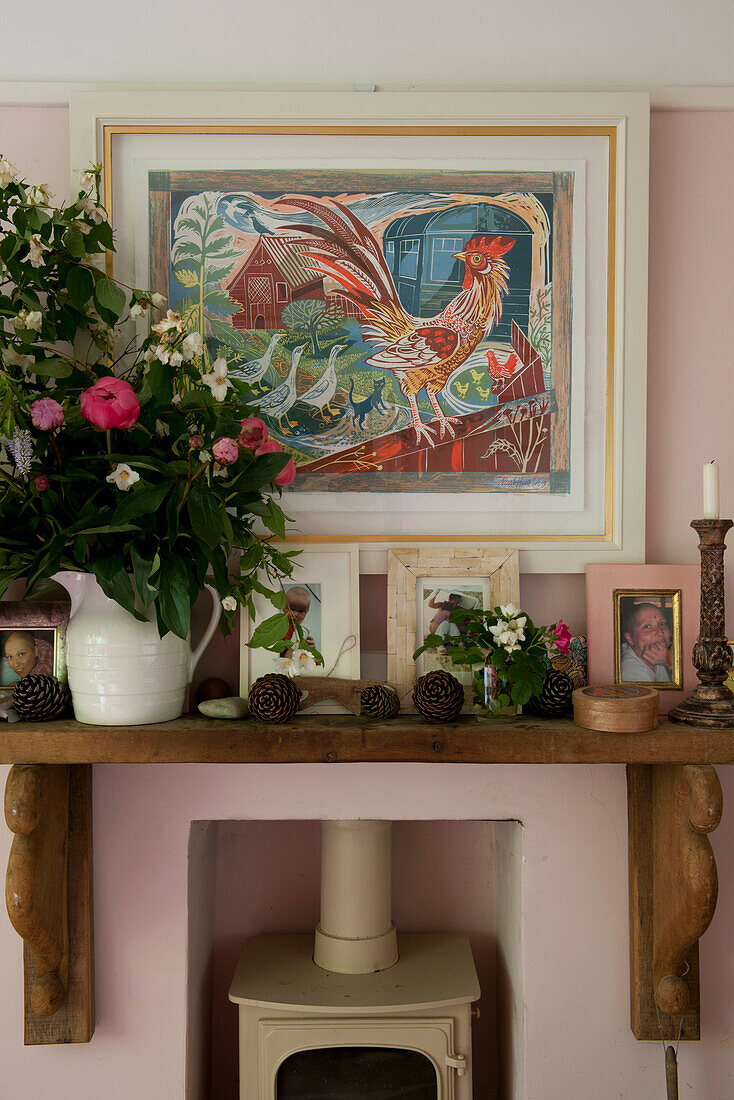 Wooden mantlepiece with artwork and cut flowers with wood burning stove in contemporary Lewes home,  East Sussex,  England,  UK