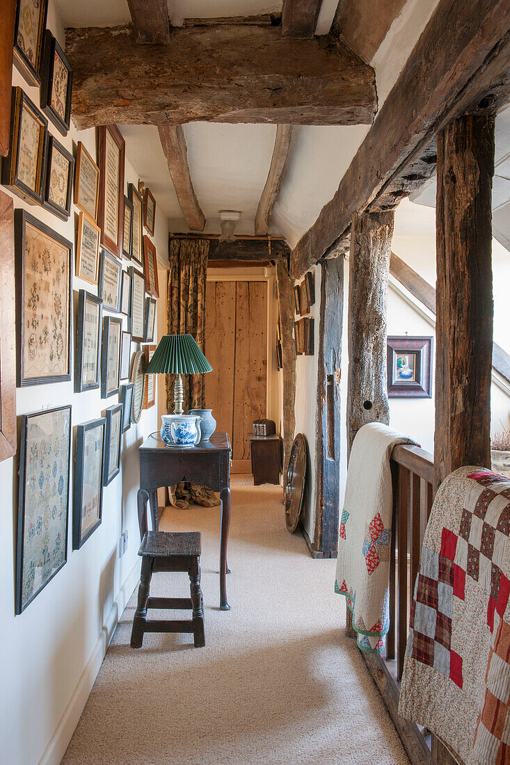 PIcture wall and patchwork quilts with beamed ceiling in farmhouse landing  Ashford  Kent  UK