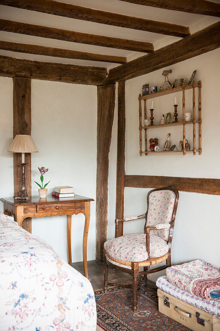 Antike Möbel und wandmontiertes Regal mit gefalteten Steppdecken in High Halden cottage Kent England UK