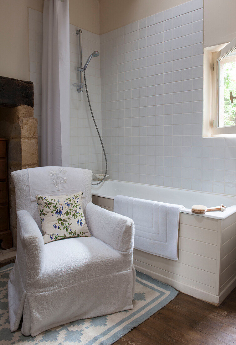 White armchair and bath in tiled bathroom of Dordogne country house  France