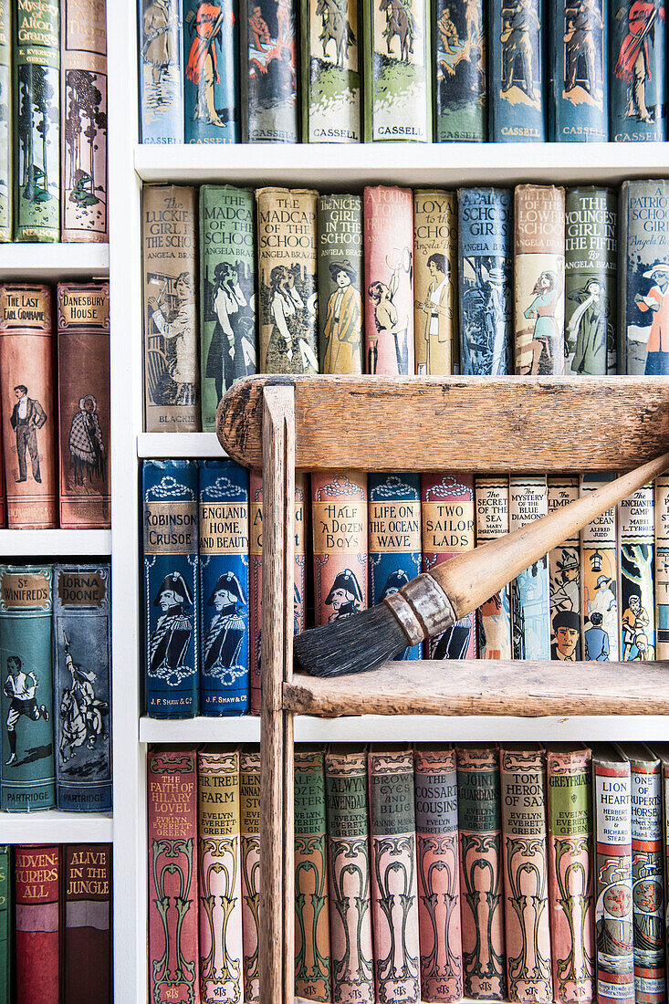 Vintage books on shelving with step ladder in Norfolk coastguards cottage  England  UK