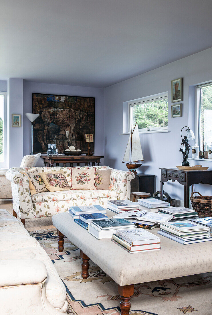 Bücher auf einer Ottomane im hellblauen Wohnzimmer eines Cottage der Küstenwache in Norfolk, England UK