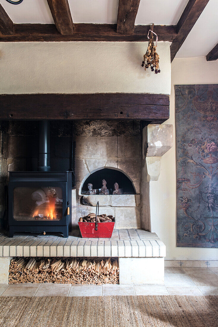 Fireplace and hearth with an arch opening into an enormous bread oven with woodburning stove and logs stored in an old boulangerie basket