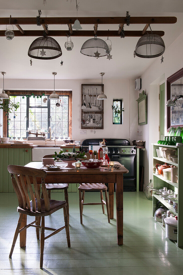 Wooden table and chairs in green kitchen of Kilndown cottage  Kent  England  UK