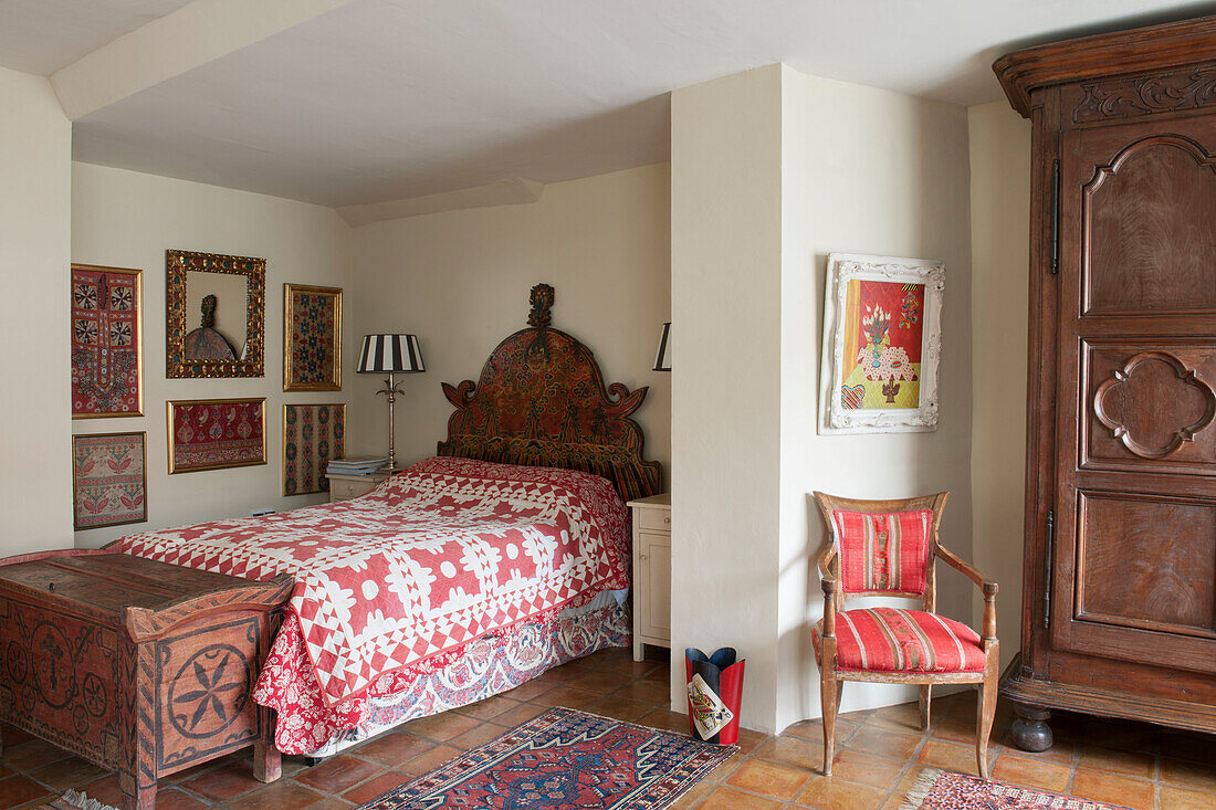 Patterned red quilt cover with decorative framed fabrics in Suffolk home  England  UK