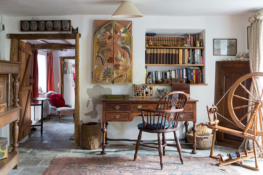 Holzstuhl am Schreibtisch mit Bücherregal und Spinnrad in einem Cottage in Devon, England UK