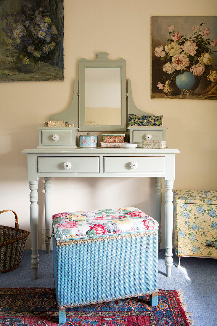 Floral stool and painted dressing table with artwork in bedroom of Amberley cottage West Sussex UK