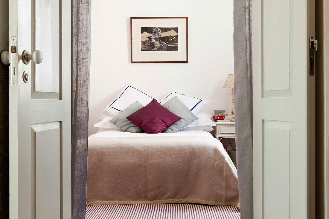 View through doorway to double bed with cushions in Castro Marim home, Portugal