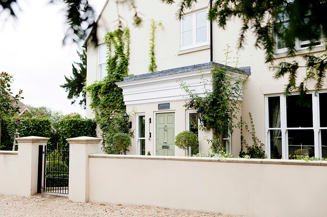 Cremefarbene Fassade eines Hauses in Amberley mit schmiedeeisernem Tor in West Sussex, England UK