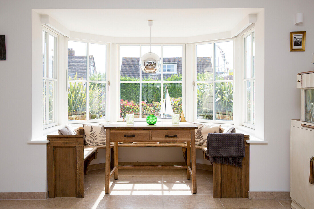 Wooden table and bench seating in window of West Wittering home West Sussex England