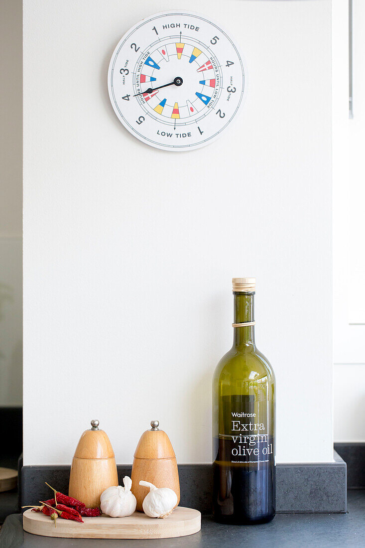 Tide clock in kitchen above salt and pepper with olive oil in West Wittering home West Sussex England