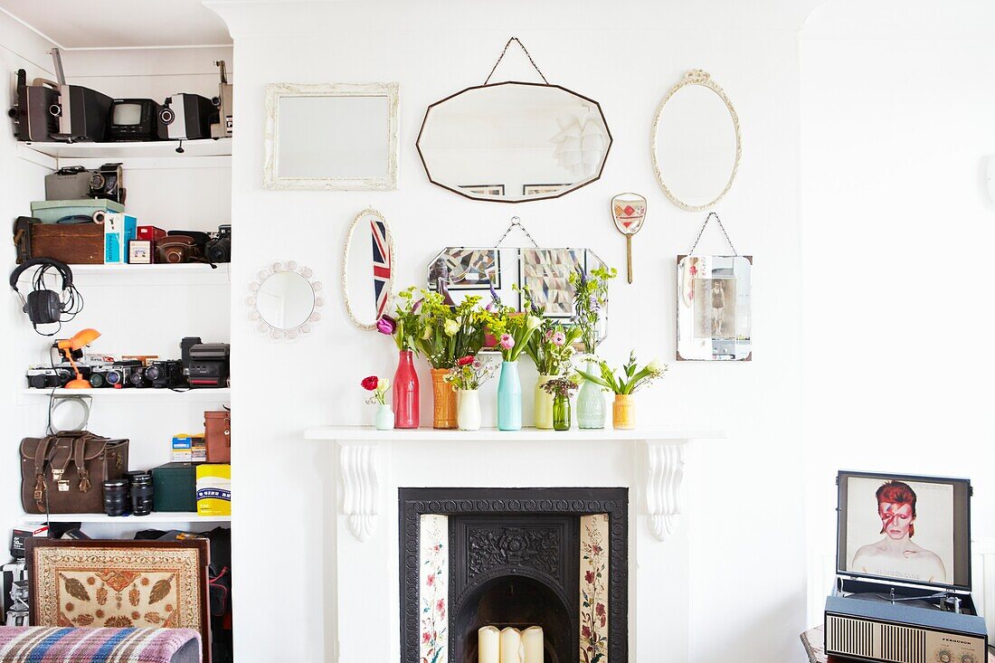 Schnittblumen auf dem Kaminsims mit Spiegeln und eingelassenen Regalen in einem Haus einer Londoner Familie, England, UK