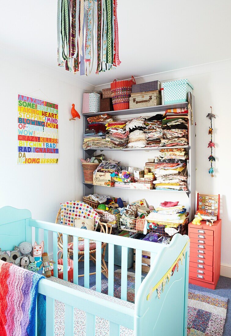 Gefaltete Kleidung auf einem Regal im Kinderzimmer mit türkisfarbenem Kinderbett, Haus einer Londoner Familie, England, UK