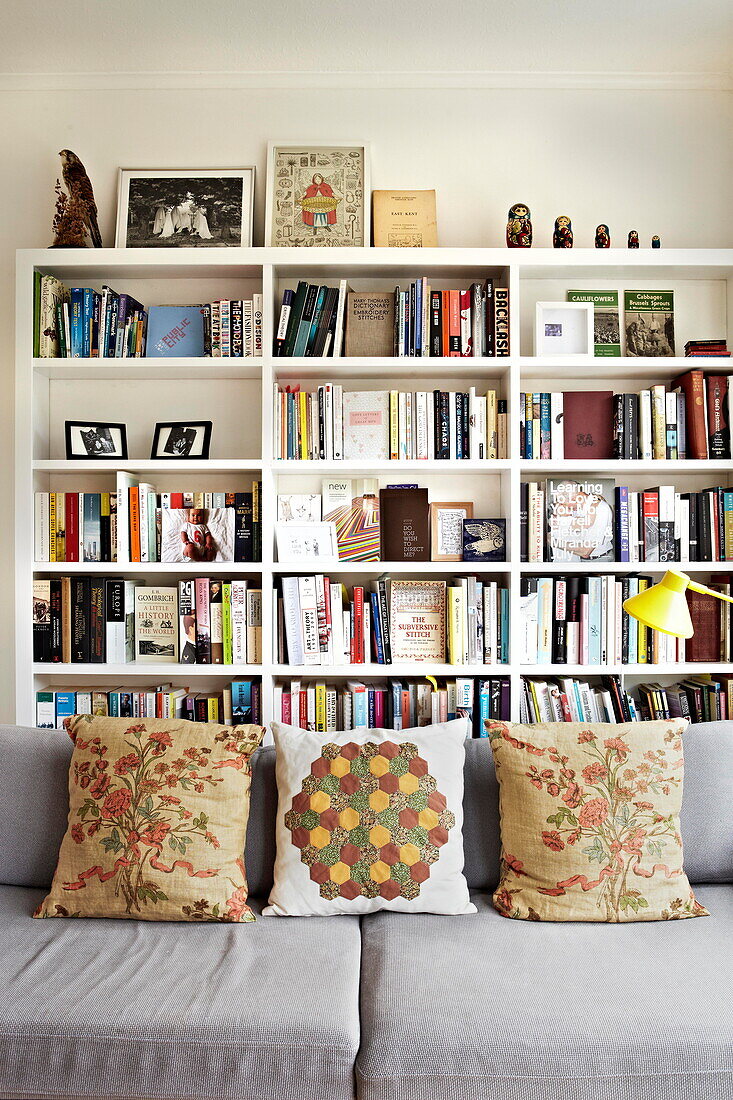 Bookcase and sofa with cushions in London family home  England  UK