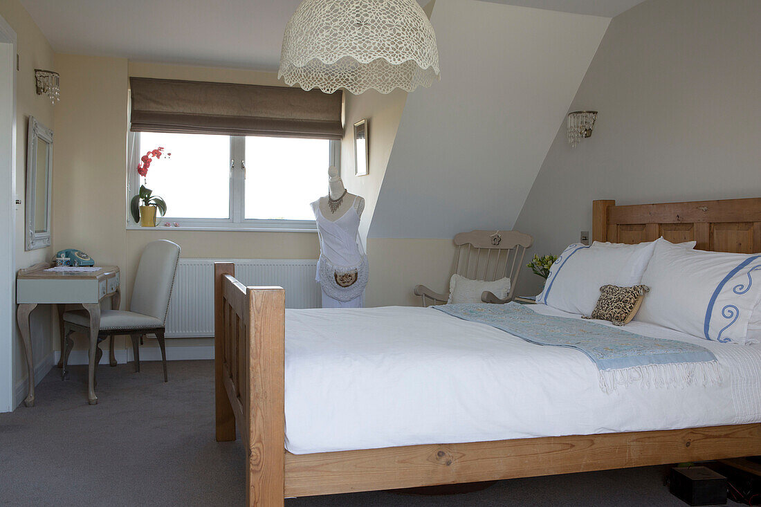 Dressmakers dummy at window with wooden bed in 1950s coastal beach house West Sussex UK