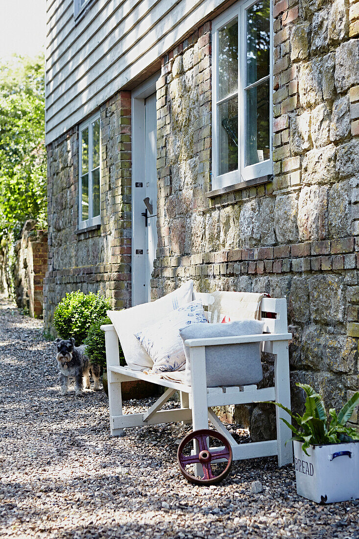 Sitzbank an der Außenseite eines Hauses in ländlicher Umgebung in Großbritannien mit Steinmauerwerk und Wetterschutzplatten