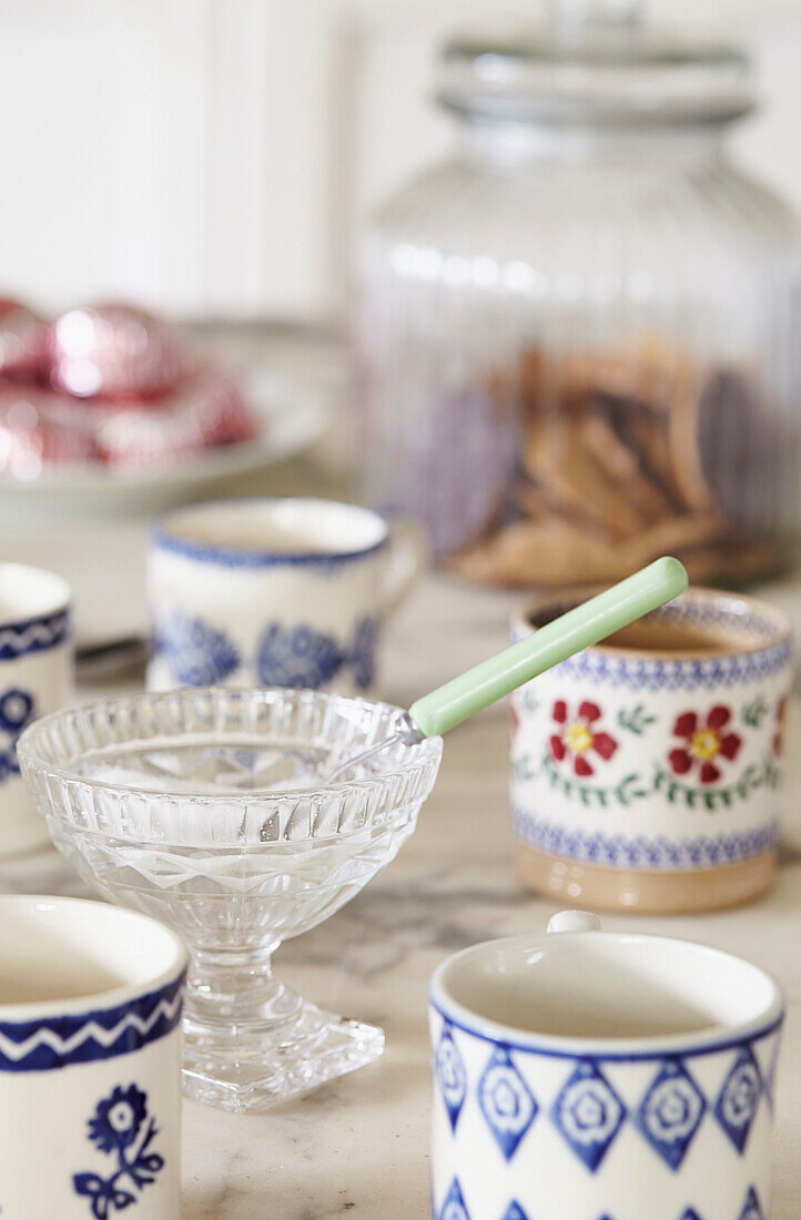 Löffel in geschliffener Glasschale mit Tassen auf dem Küchentisch im britischen Bauernhaus