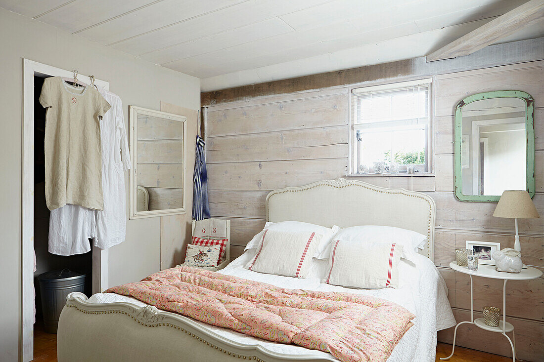 Quilt on double bed with light green mirror on panelled wall of UK farmhouse bedroom