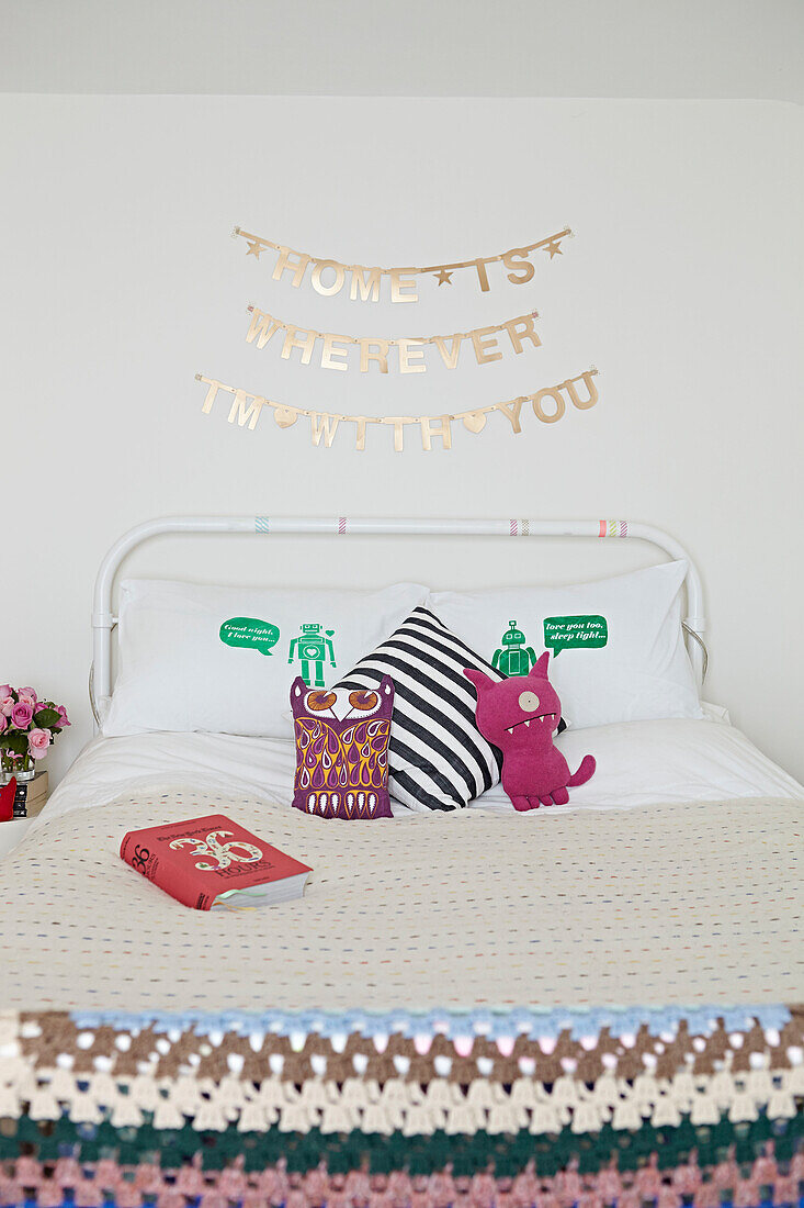 Novelty cushions on bed with crochet blanket in London home,  England,  UK