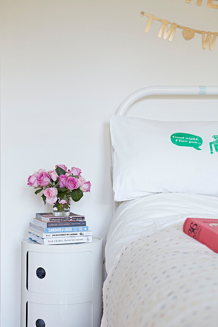 Geschnittene Rosen und Bücher auf einem Nachttisch in einem Londoner Haus in England, UK