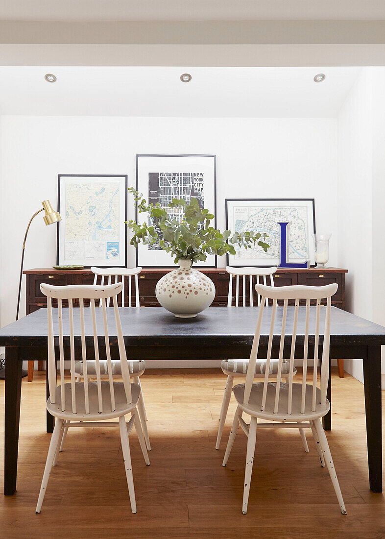 Leaf arrangement on table with white dining chairs in London home  UK