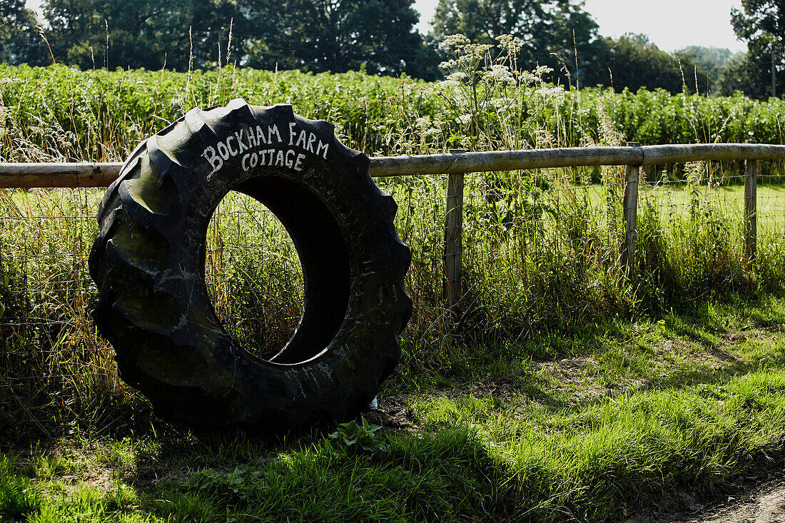 Tractor tyre on fence indicating Brabourne cottage,  Kent,  UK