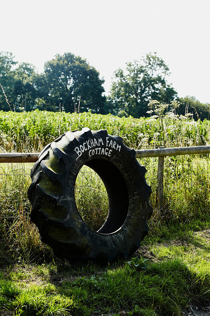 Tractor tyre on fence indicating Brabourne cottage,  Kent,  UK