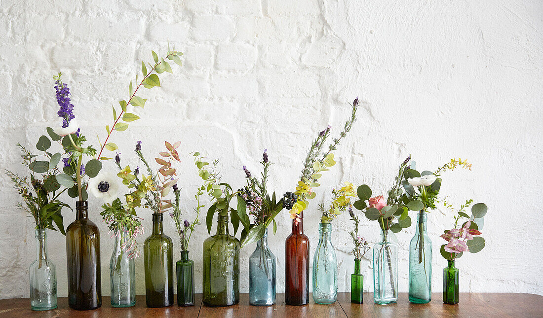 Verschiedene Blumen in alten Flaschen in einem Londoner Atelier UK